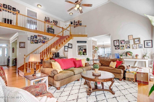 living room featuring wood-type flooring, a wealth of natural light, a high ceiling, and ornamental molding