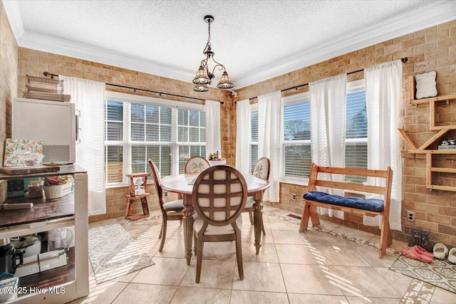 tiled dining area featuring a textured ceiling, a wealth of natural light, and brick wall