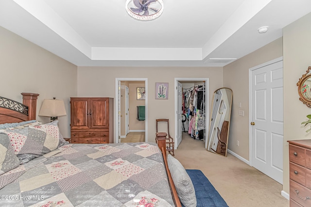 carpeted bedroom featuring a tray ceiling, a closet, and a spacious closet