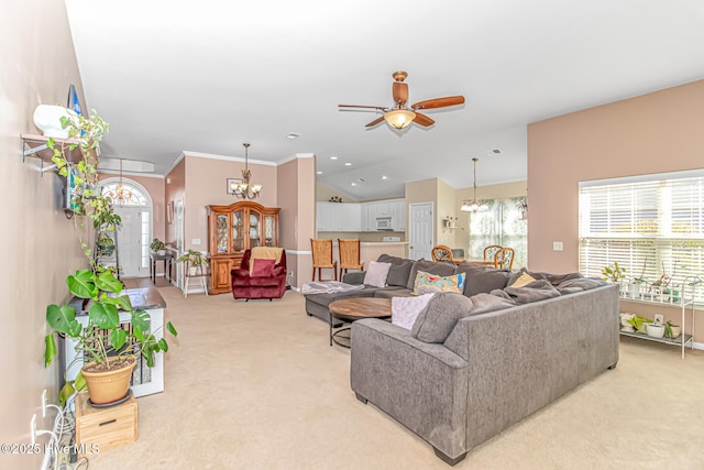 living room with vaulted ceiling, light colored carpet, a healthy amount of sunlight, and ceiling fan with notable chandelier