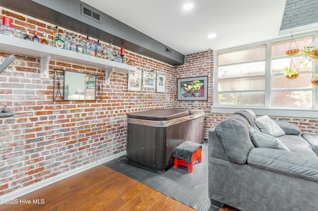 living room with brick wall, dark hardwood / wood-style flooring, and indoor bar