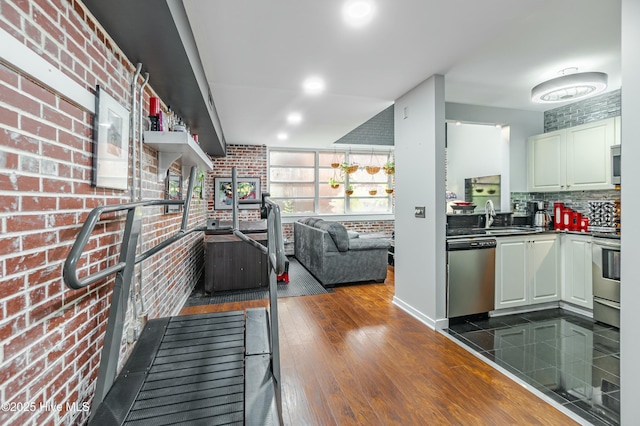 interior space with white cabinets, brick wall, and stainless steel appliances