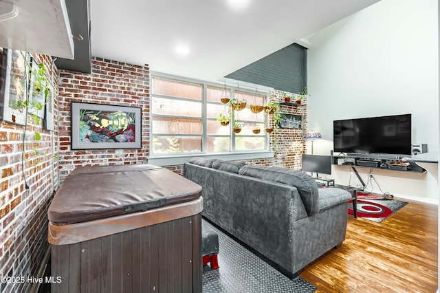 living room featuring wood-type flooring and brick wall