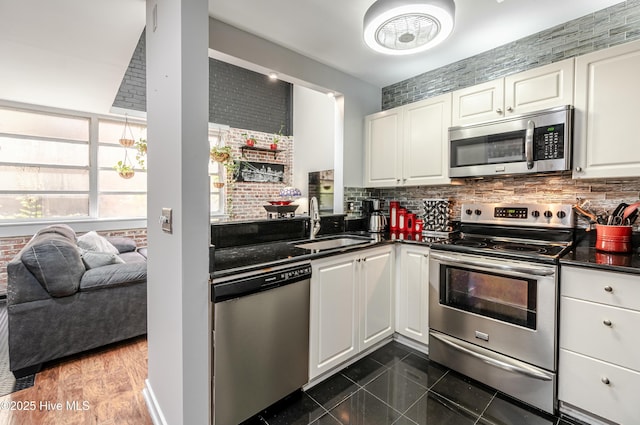 kitchen featuring tasteful backsplash, dark tile patterned flooring, sink, stainless steel appliances, and white cabinets