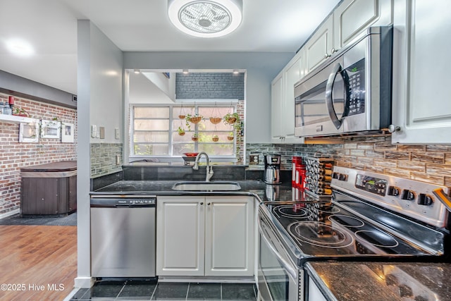 kitchen featuring sink, dark stone countertops, stainless steel appliances, and white cabinetry