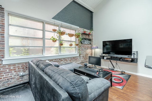 living room featuring wood-type flooring, vaulted ceiling, and brick wall