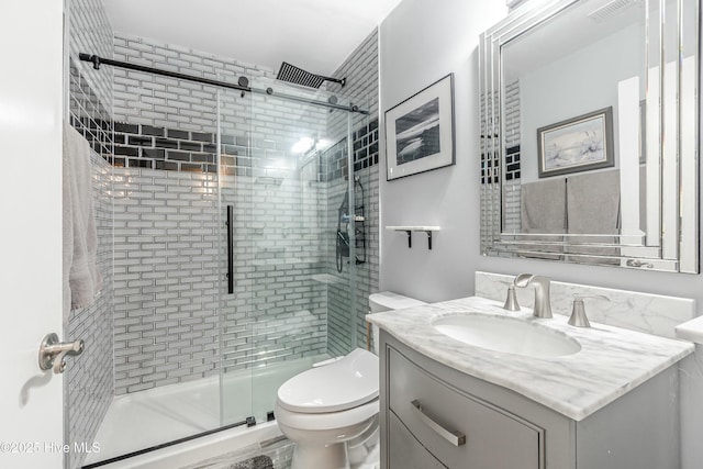 bathroom with a shower with door, toilet, and vanity