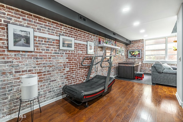 exercise area with brick wall and hardwood / wood-style flooring