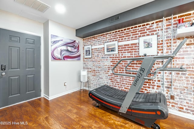 workout room featuring brick wall and hardwood / wood-style flooring