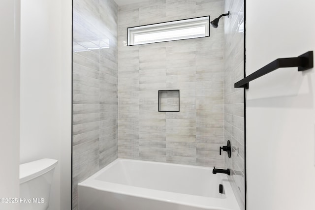 bathroom featuring toilet and tiled shower / bath combo