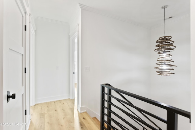 hallway featuring light hardwood / wood-style flooring, crown molding, and a chandelier