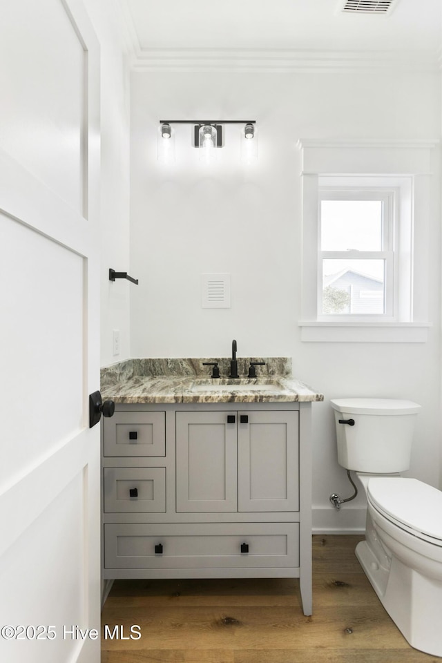 bathroom featuring hardwood / wood-style floors, toilet, vanity, and ornamental molding