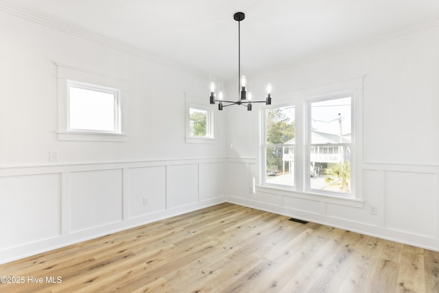 unfurnished dining area featuring a chandelier and light hardwood / wood-style flooring