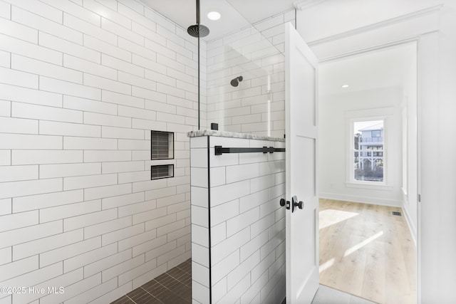 bathroom with hardwood / wood-style flooring and tiled shower