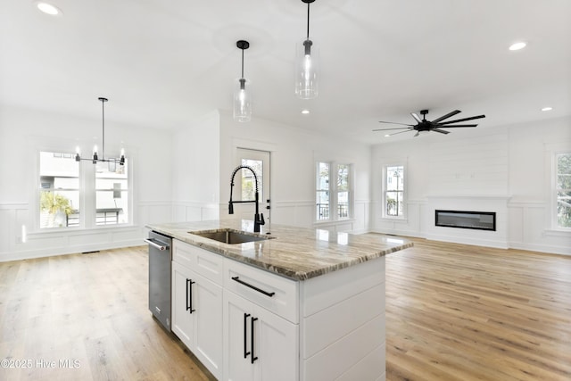 kitchen featuring light stone countertops, white cabinetry, pendant lighting, and sink