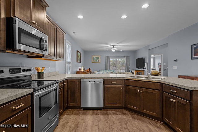 kitchen featuring sink, light hardwood / wood-style flooring, stainless steel appliances, dark brown cabinetry, and kitchen peninsula