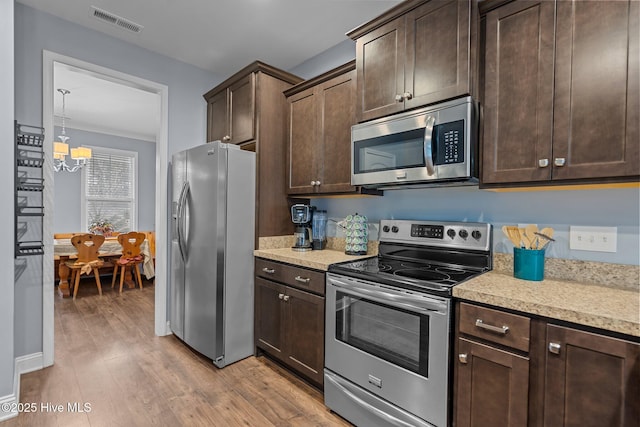 kitchen with appliances with stainless steel finishes, dark brown cabinets, and light hardwood / wood-style floors