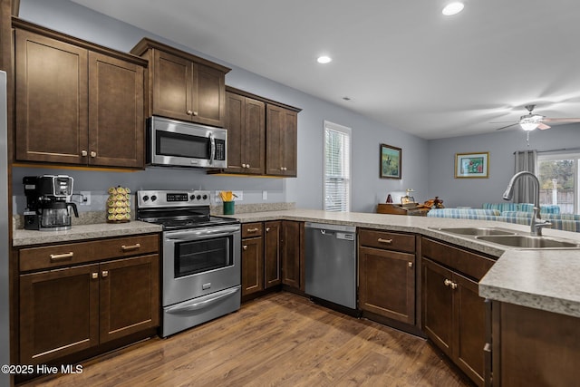 kitchen featuring sink, hardwood / wood-style floors, dark brown cabinets, stainless steel appliances, and kitchen peninsula