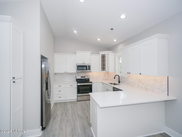 kitchen with tasteful backsplash, kitchen peninsula, appliances with stainless steel finishes, and white cabinetry