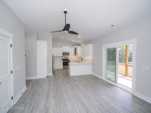 kitchen featuring lofted ceiling, ceiling fan, decorative backsplash, white cabinetry, and appliances with stainless steel finishes