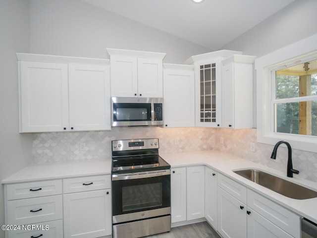 kitchen with sink, backsplash, appliances with stainless steel finishes, and white cabinets