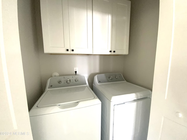 laundry room featuring washing machine and clothes dryer and cabinets