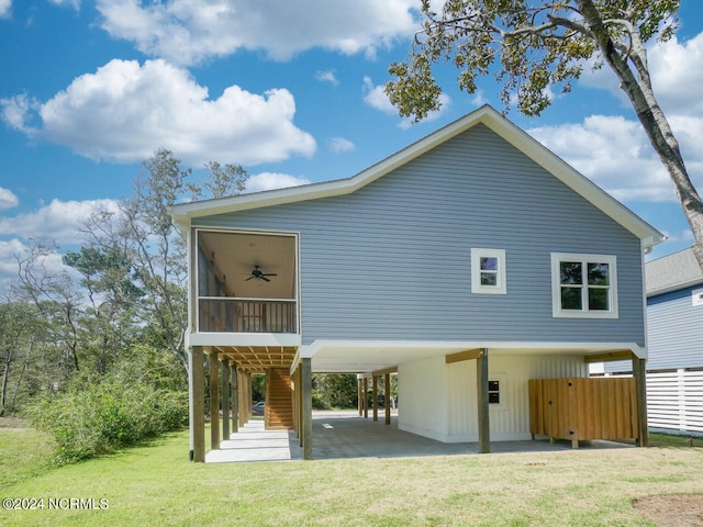 rear view of house with ceiling fan, a sunroom, a yard, and a carport