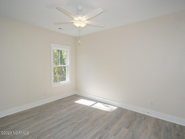 spare room with ceiling fan, hardwood / wood-style floors, and a raised ceiling