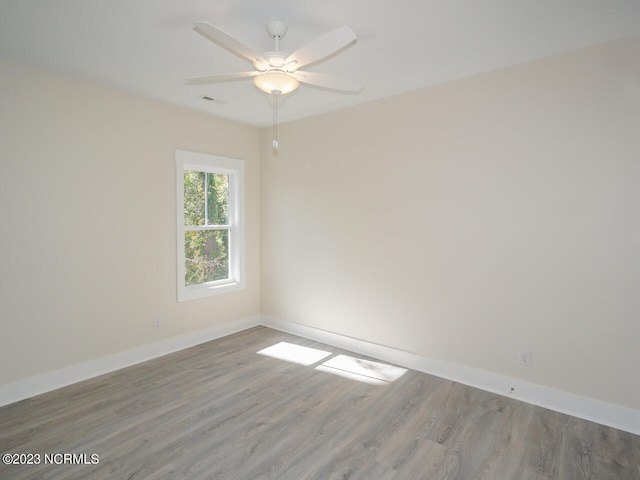 unfurnished room featuring visible vents, ceiling fan, baseboards, and wood finished floors