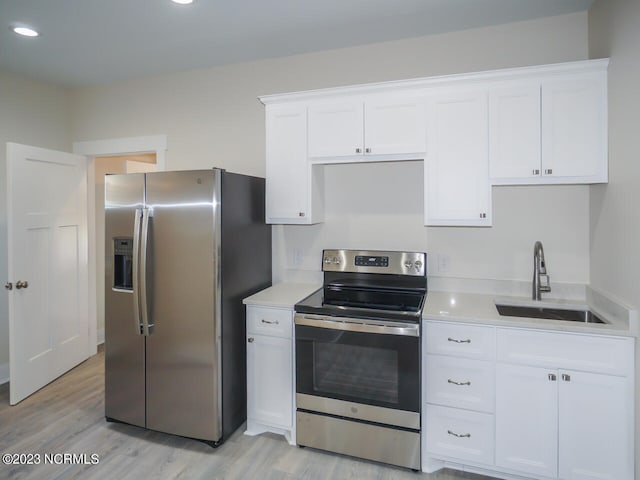 kitchen with a sink, stainless steel appliances, white cabinetry, and light countertops