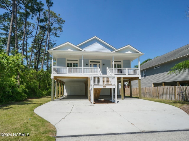 raised beach house featuring a front lawn, a carport, covered porch, and driveway