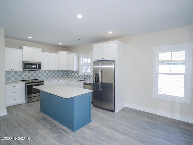 kitchen featuring stainless steel appliances, sink, white cabinets, and a center island