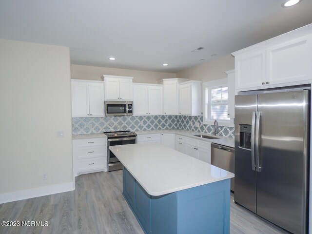 kitchen with stainless steel appliances, light hardwood / wood-style floors, white cabinets, and sink