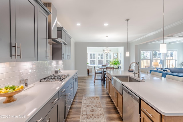 kitchen with crown molding, appliances with stainless steel finishes, sink, decorative light fixtures, and wall chimney range hood