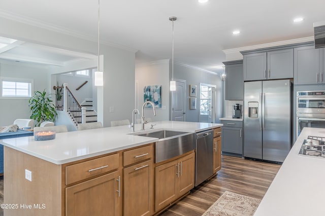 kitchen featuring pendant lighting, appliances with stainless steel finishes, gray cabinets, and a center island with sink