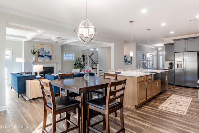 dining space with crown molding, dark hardwood / wood-style flooring, sink, coffered ceiling, and beamed ceiling