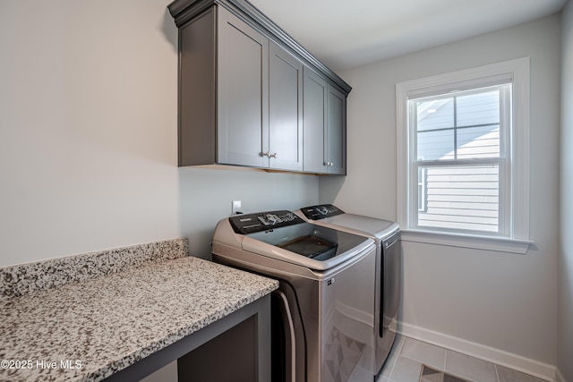 laundry area featuring light tile patterned flooring, cabinets, washing machine and dryer, and a wealth of natural light