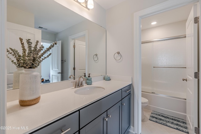 full bathroom with bath / shower combo with glass door, toilet, vanity, and tile patterned flooring