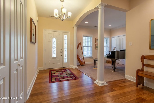 foyer entrance with ornate columns, ornamental molding, and hardwood / wood-style flooring