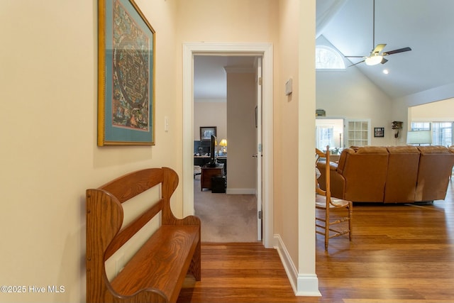 corridor with wood-type flooring and high vaulted ceiling