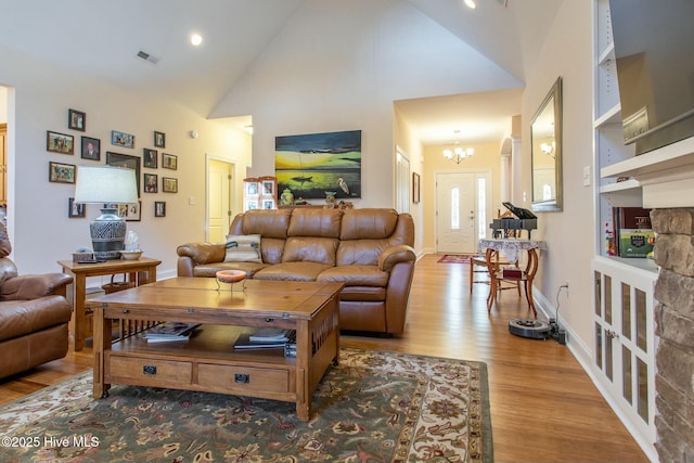 living room featuring an inviting chandelier, high vaulted ceiling, and light hardwood / wood-style floors