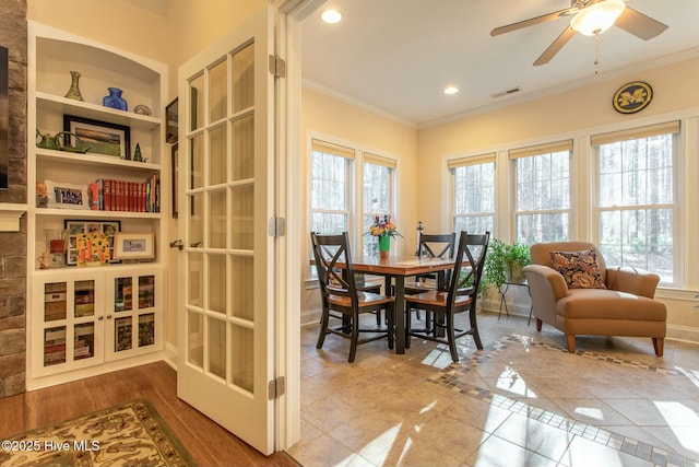 tiled dining room with ceiling fan, crown molding, and built in shelves