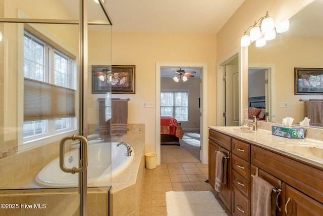 bathroom with a relaxing tiled tub, vanity, and tile patterned flooring