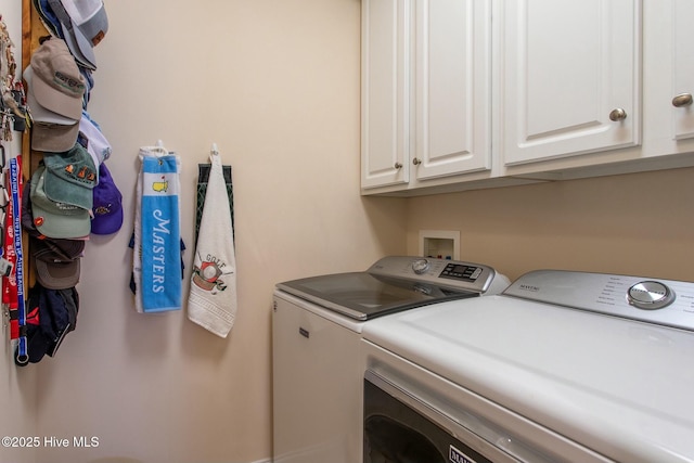 clothes washing area with cabinets and separate washer and dryer