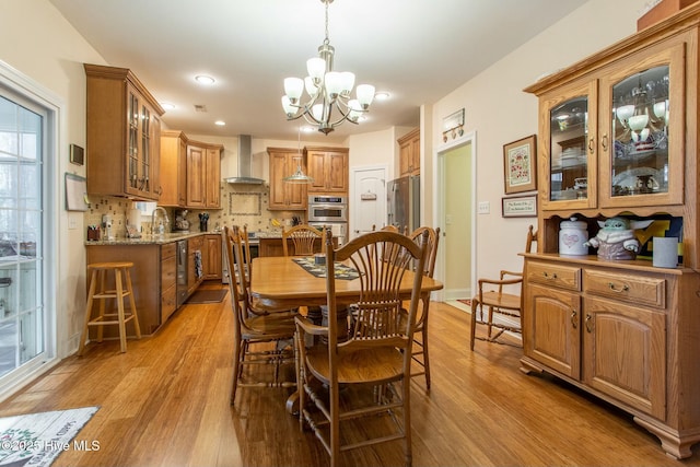 dining space with a notable chandelier, sink, and light wood-type flooring