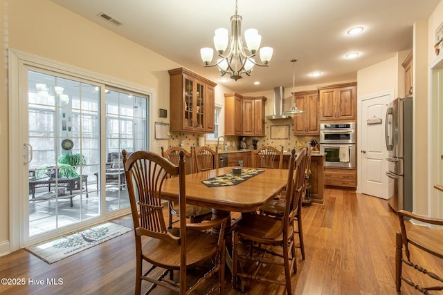 dining room featuring wood-type flooring, sink, and an inviting chandelier