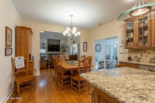 dining area featuring a large fireplace, hardwood / wood-style floors, and an inviting chandelier