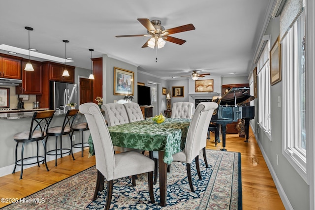 dining space with light wood-style floors, a fireplace, and baseboards