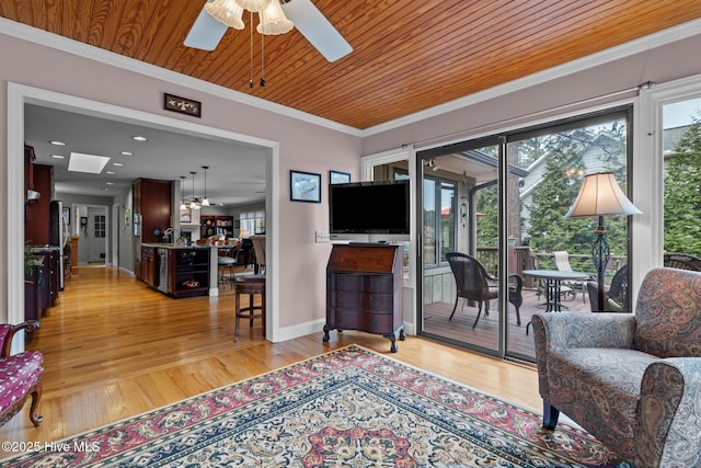 living room featuring a wealth of natural light, light wood-style floors, wood ceiling, and crown molding