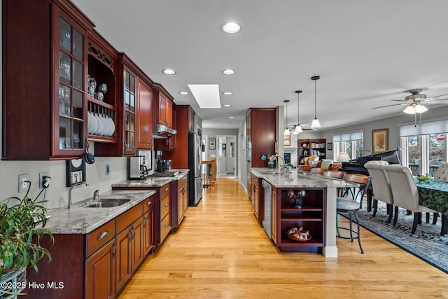 kitchen with a breakfast bar area, open floor plan, a peninsula, stainless steel appliances, and a sink